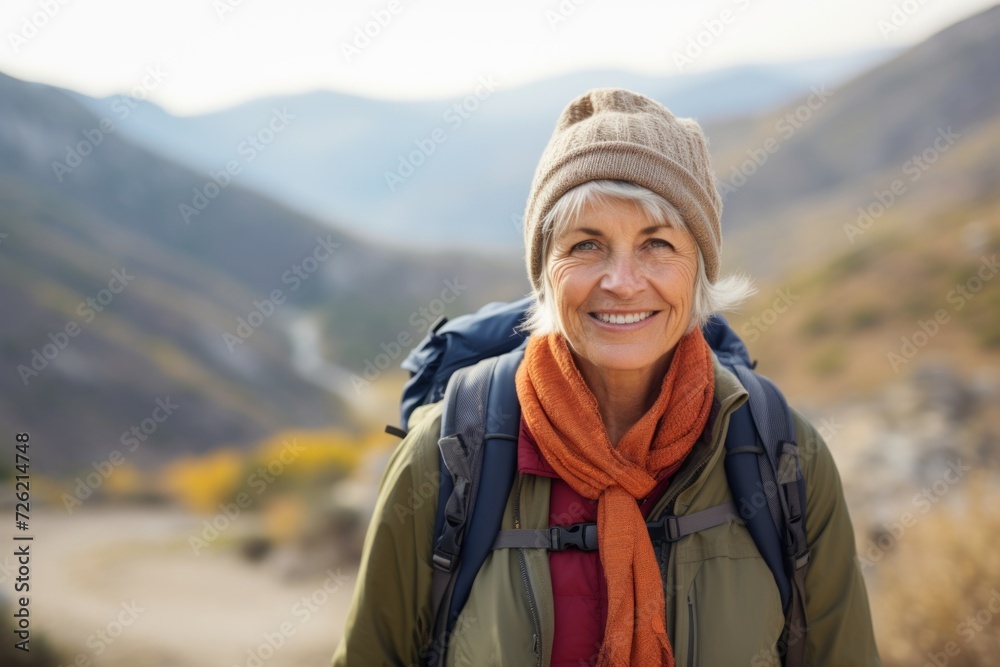 Portrait of a smiling senior woman with a backpack in the mountains