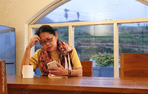 Woman sitting in the dining room reading messages from her smartphone photo