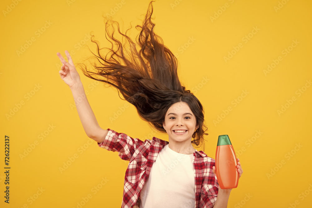 Child teen girl with shampoos conditioners and shower gel. Long hair care of teenager. Presenting cosmetic product, shampoo bottle. Amazed teenager. Excited teen girl. Child teen girl with shampoos conditioners and shower gel. Long hair care of teenager. Presenting cosmetic product, shampoo bottle. Amazed teenager. Excited teen girl.