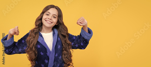 in good mood. sleepy kid stretching sleepily. smiling child wearing comfortable pajama. Child face, horizontal poster, teenager girl isolated portrait, banner with copy space. photo