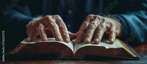 A person's hands engaged in reading a book or being in church, a place of worship for the Christian community, to honor and worship Jesus Christ, the Holy Spirit, and the teachings of the Bible. photo