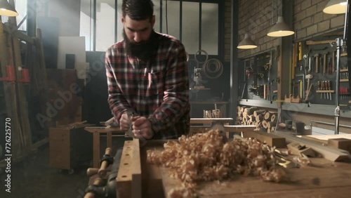 Carpenter planing wood in moody workshop photo