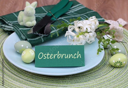 Text Osterbrunch auf einer Tischkarte mit Besteck Blumen und Ostereiern.