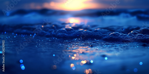 In the early dawn light on the open sea over ultramarine fluorescent sea wave in focus, beautiful bokeh of sag lights