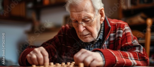 Elderly man concentrating on memory exercise, solving logic test at table, related to neurology.