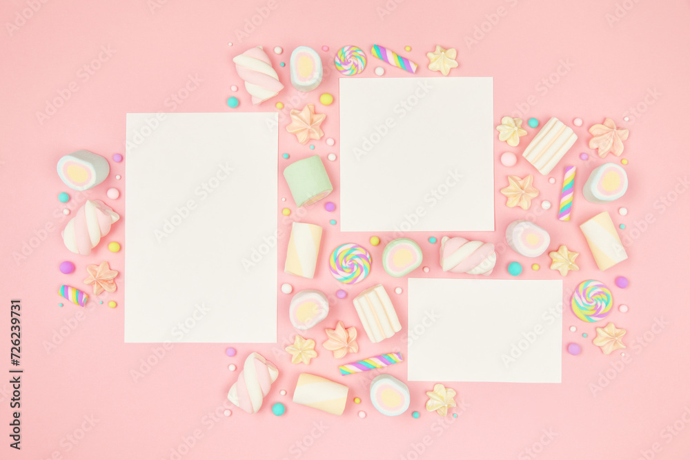 Set of three blank white cards on cute pastel pink kawaii background with frame of sweet candies, meringue and marshmallows . Flat lay, top view, copy space. Beautiful childlike design template