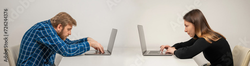 Young woman and emotional man in slouching position sitting in office room, working with laptop