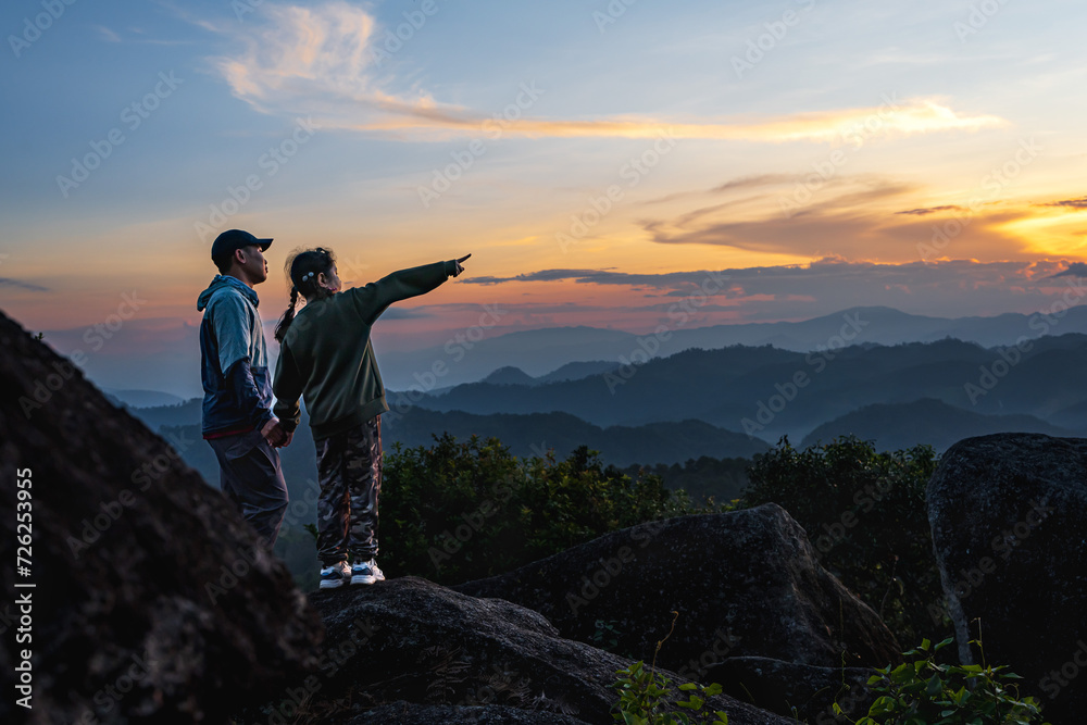 Hiker father and daughter standing at top of the mountains Hiker father and daughter standing at top of the mountains