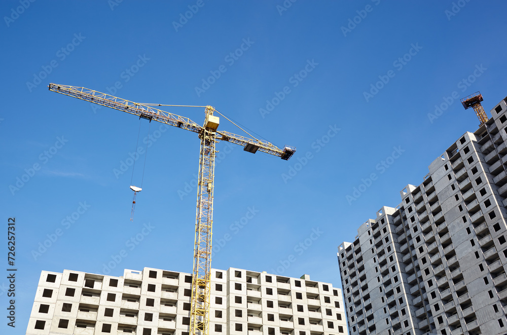 Tower crane building a house. Concrete building under construction. Construction site