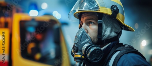 Confident firefighter, wearing uniform and helmet, holding an oxygen mask and glancing sideways. photo