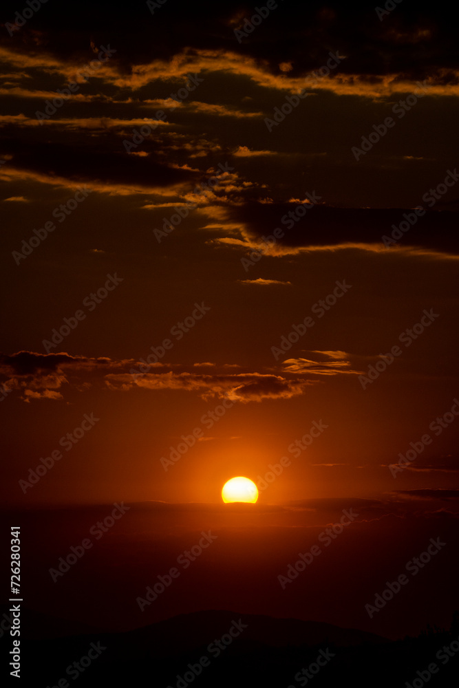 Beautiful sunset in the mountains. Sunset View from the Top of a Mountain. Sunset in strong orange tones in Serbia. The sun falls for horizon, a sunset. Shadows are condensed, beautiful clouds. 
