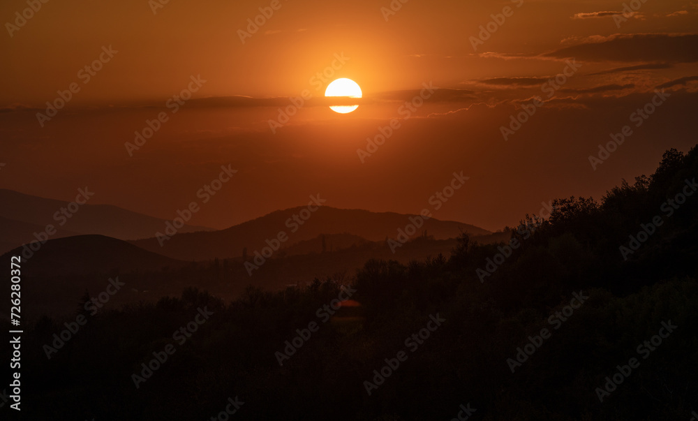 Beautiful sunset in the mountains. Sunset View from the Top of a Mountain. Sunset in strong orange tones in Serbia. The sun falls for horizon, a sunset. Shadows are condensed, beautiful clouds. 