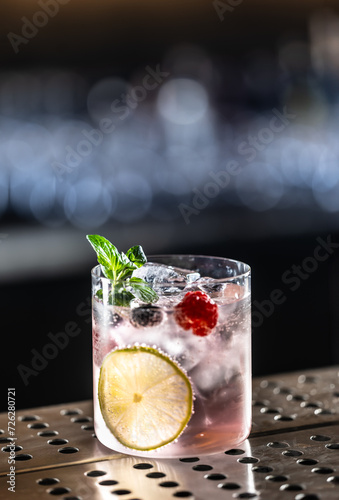 Pink cocktail Gin Tonic drink with raspberries, blueberries, lime and fresh mint