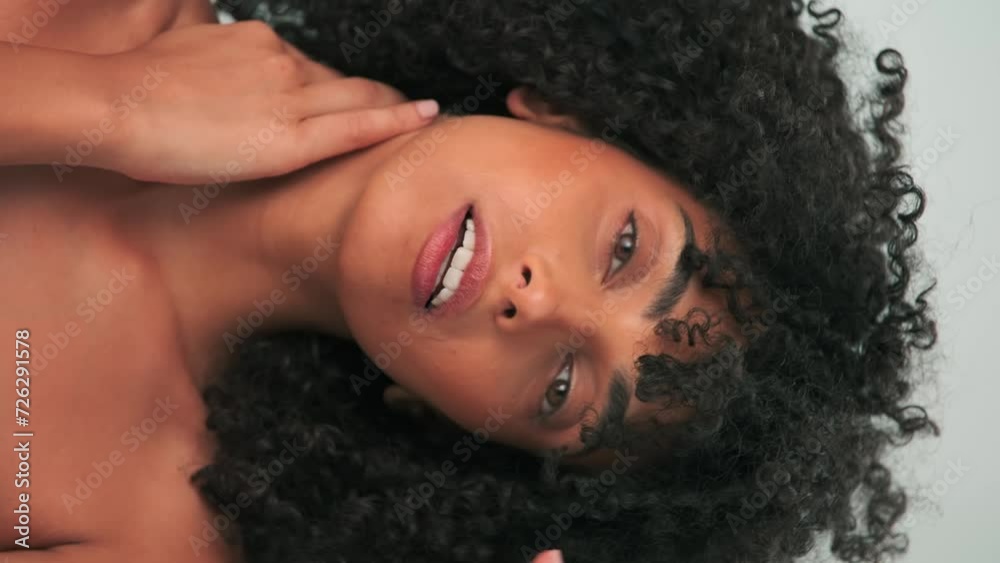 Vertical portrait of young smiling model with curly hair in afro style and bright makeup