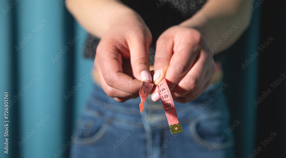 Young caucasian woman holding measuring tape.