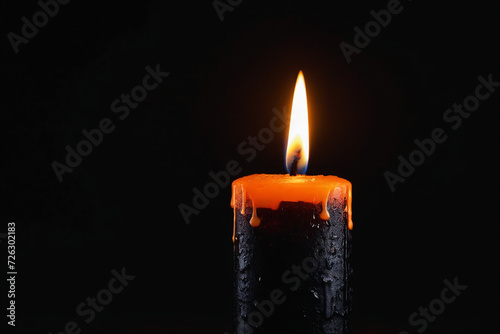 Black candle burning with streaks of paraffin on dark background