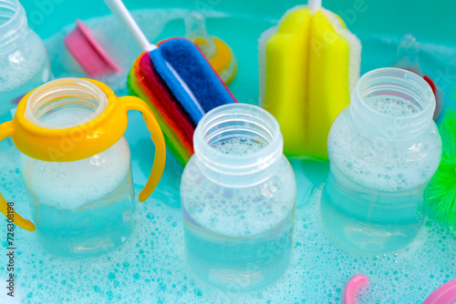Wash baby bottles in plastic blue basin