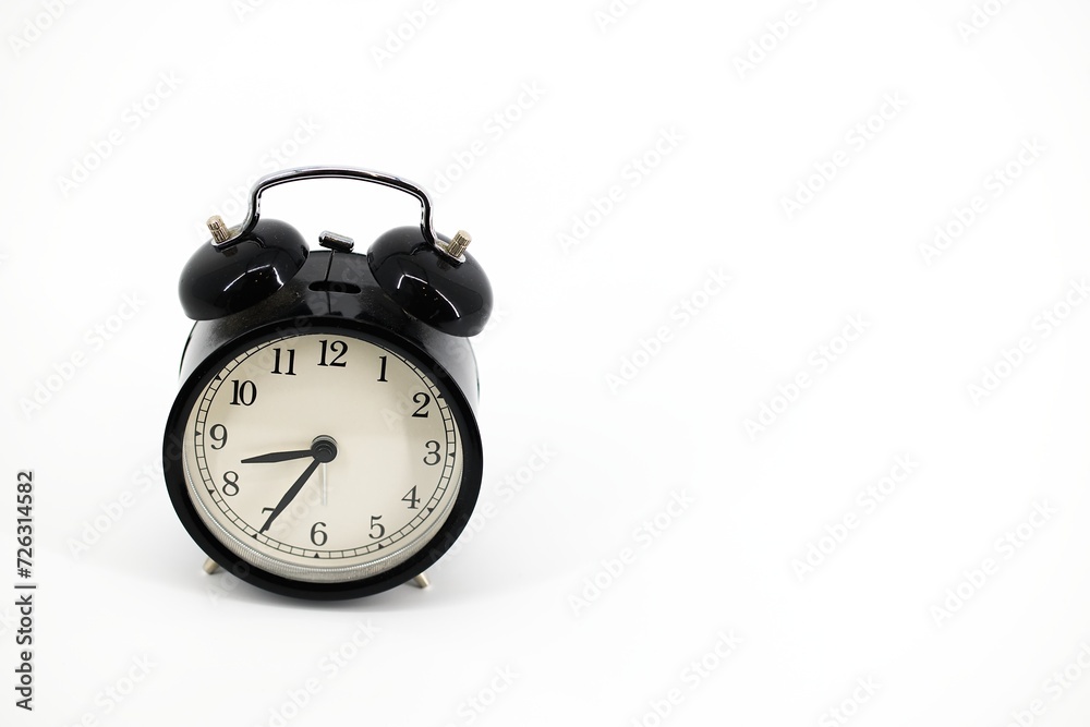 A black alarm clock with two bells on top, chrome handle, and legs, set against a white background. Timeless design meets functionality in this sleek, monochromatic timepiece.. A black alarm clock with two bells on top, chrome handle, and legs, set against a white background. Timeless design meets functionality in this sleek, monochromatic timepiece..