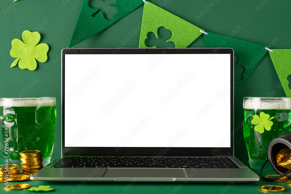 St. Patrick's Day theme: side view photo of laptop open for virtual celebrations, frothy beer mugs, scattered gold coins, pot, and trefoil flag streamers on a vibrant green surface with space for text - obrazy, fototapety, plakaty 