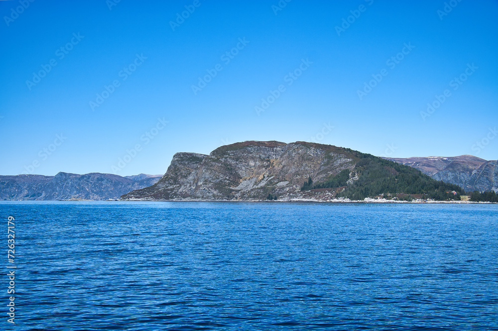 Western cap in Norway. A mountain reaching into the fjord. Blue sky. Landscape