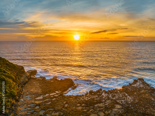 Sunrise over the sea and rock platform with high cloud