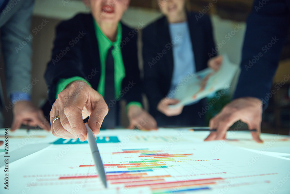 Business people, project leaders pointing at colorful business charts on table, discussing data, statistics and doing analytical researches for profitable and successful growth. Concept of business Business people, project leaders pointing at colorful business charts on table, discussing data, statistics and doing analytical researches for profitable and successful growth. Concept of business