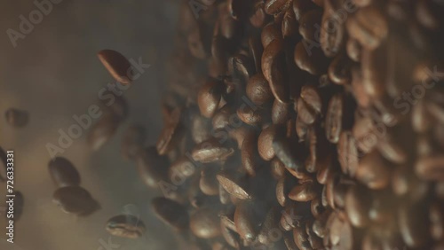 Super slow motion shot of falling roasted coffee beans with smoke in macro. Vertical close up video photo