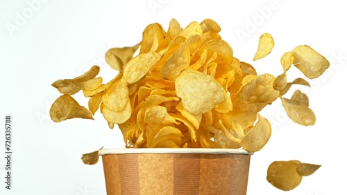 Flying Fried Potato Chips Exploding from Paper Bucket. Concept of Flying Junk Food.