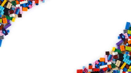 Close-up of cluttered piles of colorful toy bricks viewed from above with place for content or text. Isolated on white background, top view. Copy space.
