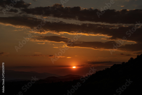 Beautiful sunset in the mountains. Sunset View from the Top of a Mountain. Sunset in strong orange tones in Serbia. The sun falls for horizon  a sunset. Shadows are condensed  beautiful clouds. 