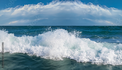 Powerful foamy sea waves rolling and splashing over water surface against cloudy blue sky, panoramic image with copy space