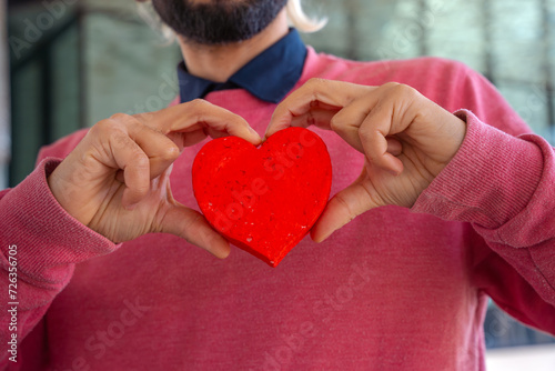  Portrait of a smiling young man holding a heart on Valentine's Day outdoors. photo