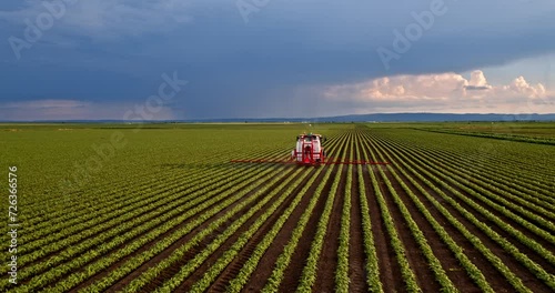 Farmer spraying soybean crops from tractor in aerial view photo