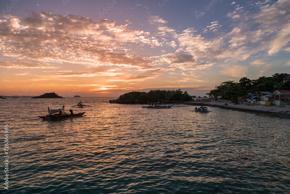 Sunset time in Malapascua island. Sunset colorful sky. Landscape photo with beach and boats in ocean water.