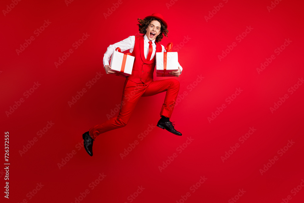 Full length body photo of jumping and running student prepared for festival secret santa gifts holiday isolated on red color background