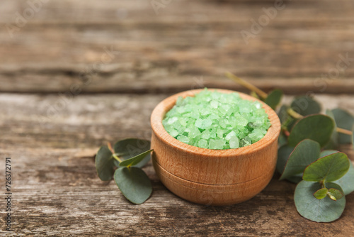 Cosmetic sea salt with aroma and eucalyptus extract on a textured wooden background with branches of fresh aromatic eucalyptus.Spa concept. Bath salt. Close-up. Space for text.Body care.copy space