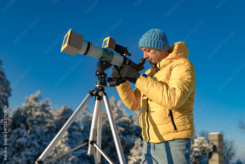 Amateur astronomer looking at the Sun trough a telescope with special solar filter.