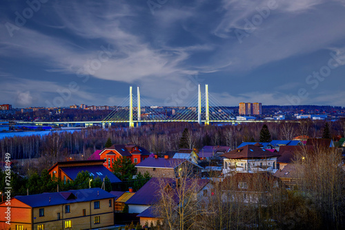 View of the silhouette of the illuminated bridge in selective focus, Cherepovets against the background of the evening sky with beautiful scattered stratus clouds. photo