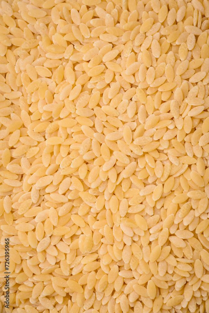 Raw risoni pasta made from durum wheat on a dark concrete background Raw risoni pasta made from durum wheat on a dark concrete background