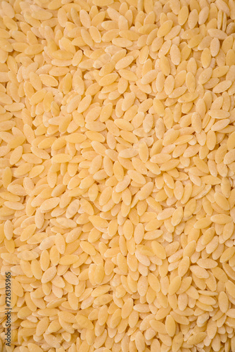 Raw risoni pasta made from durum wheat on a dark concrete background photo