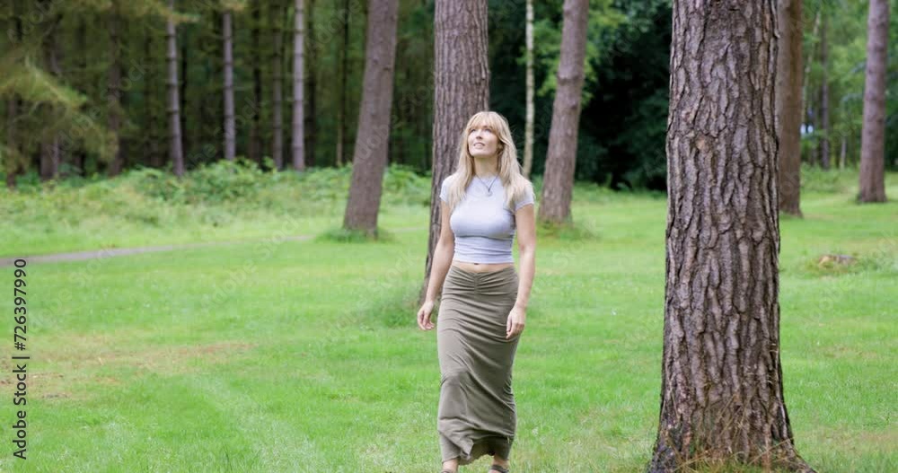 Blond woman walking in forest looking around Blond woman walking in forest looking around
