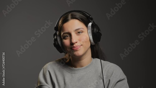 Girl in headphones. Girl puts on black headphones and dances to the beat. Girl measures large wired headphones. Music in headphones. Body movement. Smile. Young brunette girl slowly moving her head to