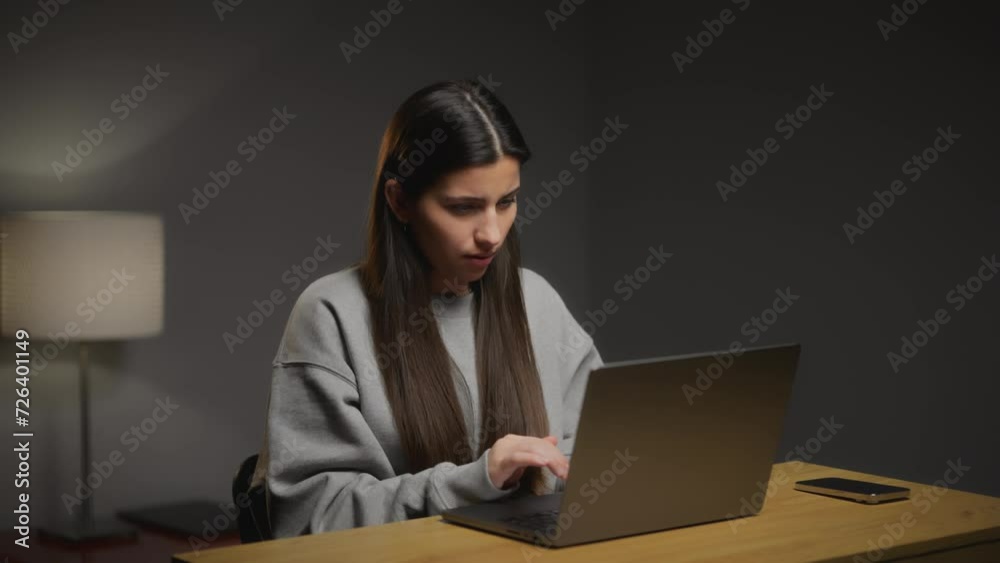 A young girl works at her laptop. The girl writes an e-mail. Working process. Gray background. Working atmosphere. A young woman working with a laptop. Young woman busy doing work. Keyboard. The girl A young girl works at her laptop. The girl writes an e-mail. Working process. Gray background. Working atmosphere. A young woman working with a laptop. Young woman busy doing work. Keyboard. The girl