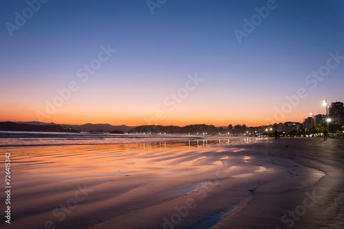 City of Santos  Brazil. Sunset at the beach. Reflection of the sky in the water mirror on the sand strip.