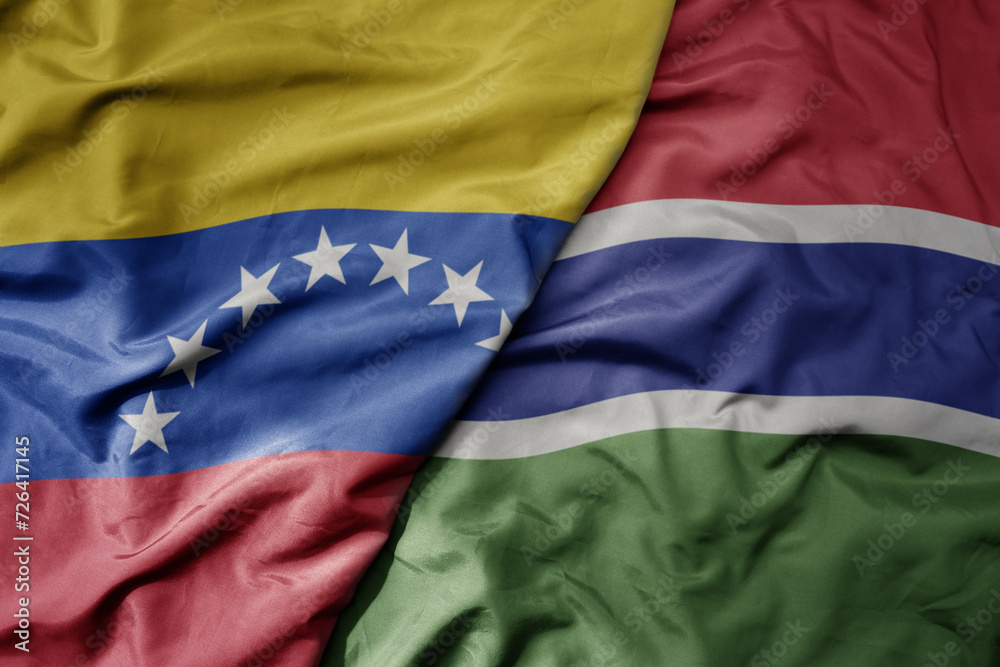 Fototapeta premium big waving national colorful flag of gambia and national flag of venezuela . macro