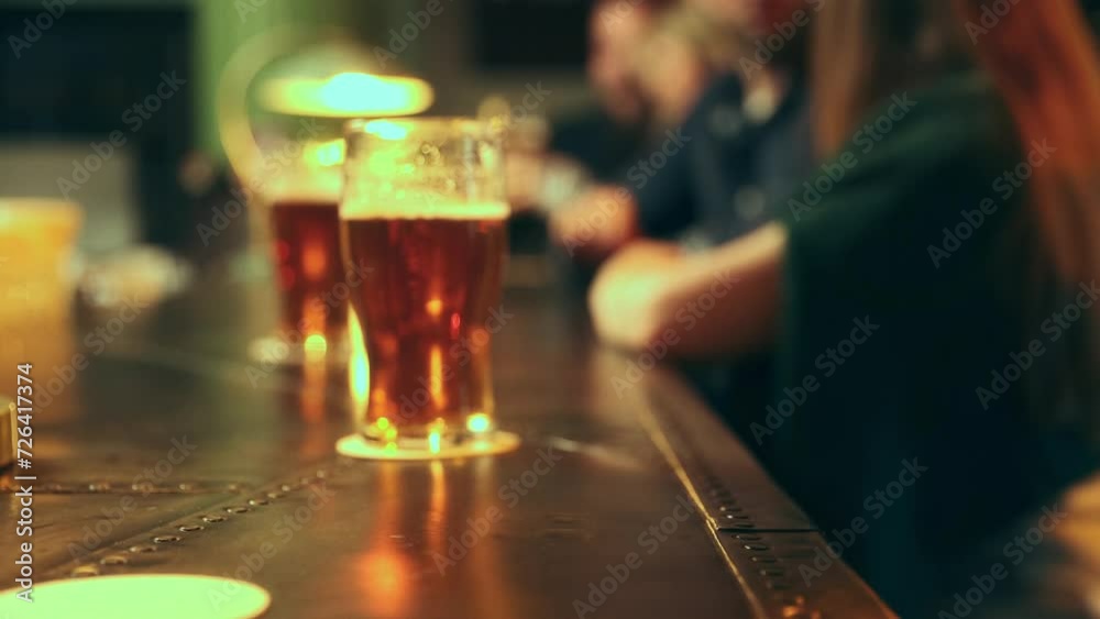 Focus on bar and beer glasses. People taking glasses with foamy lager beer. Friends meeting in pub, having fun, drinking and talking. Concept of leisure time, friendship, fun and joy, youth, enjoyment