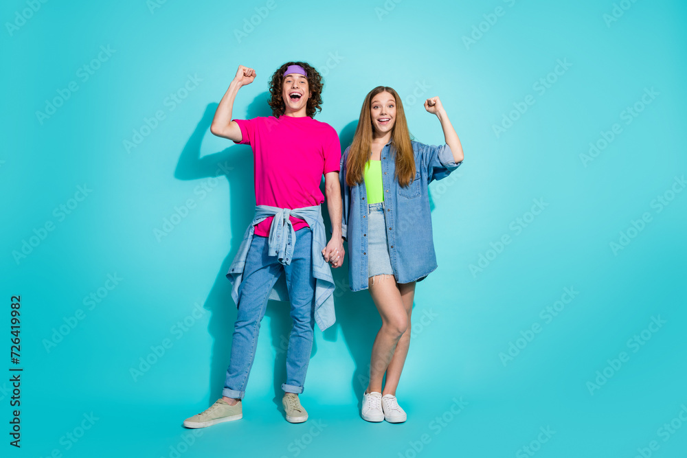 Obraz premium Full body photo of two youth teenagers fists up holding arms together achievement in relationships isolated on aquamarine color background