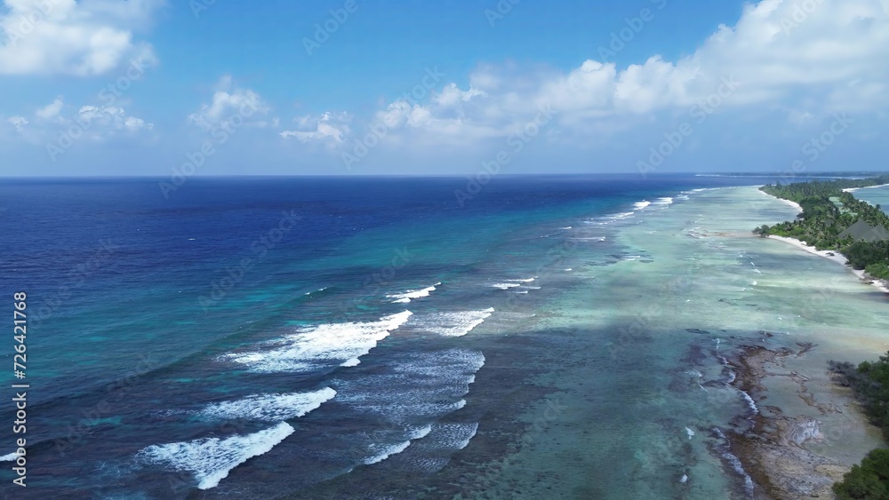 Fototapeta premium Drone view of paradise islands of the Maldives with coral reefs under the waves of blue the Indian Ocean.