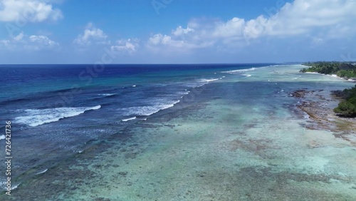 Drone view of paradise islands of the Maldives with coral reefs under the waves of blue the Indian Ocean. © Michael