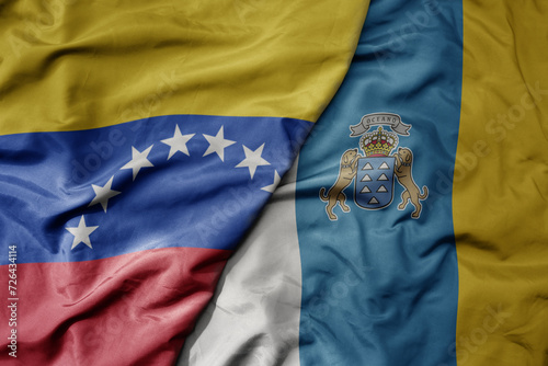 big waving national colorful flag of canary islands and national flag of venezuela . macro